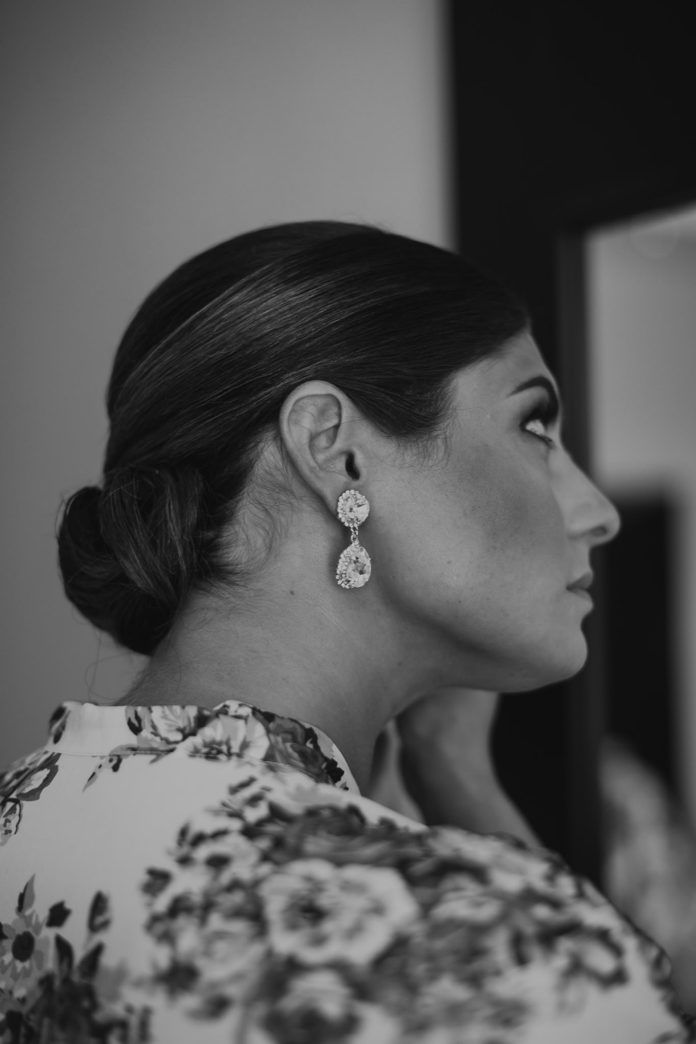 Black-and-white side profile showing an elegant low bridal updo and statement earrings